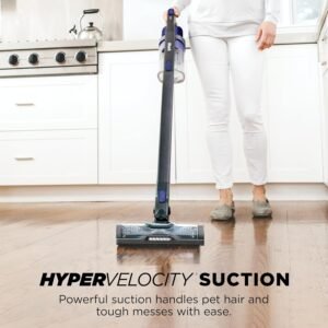 The Shark Pet Cordless Stick Vacuum with its flexible wand bent to clean under a low coffee table.